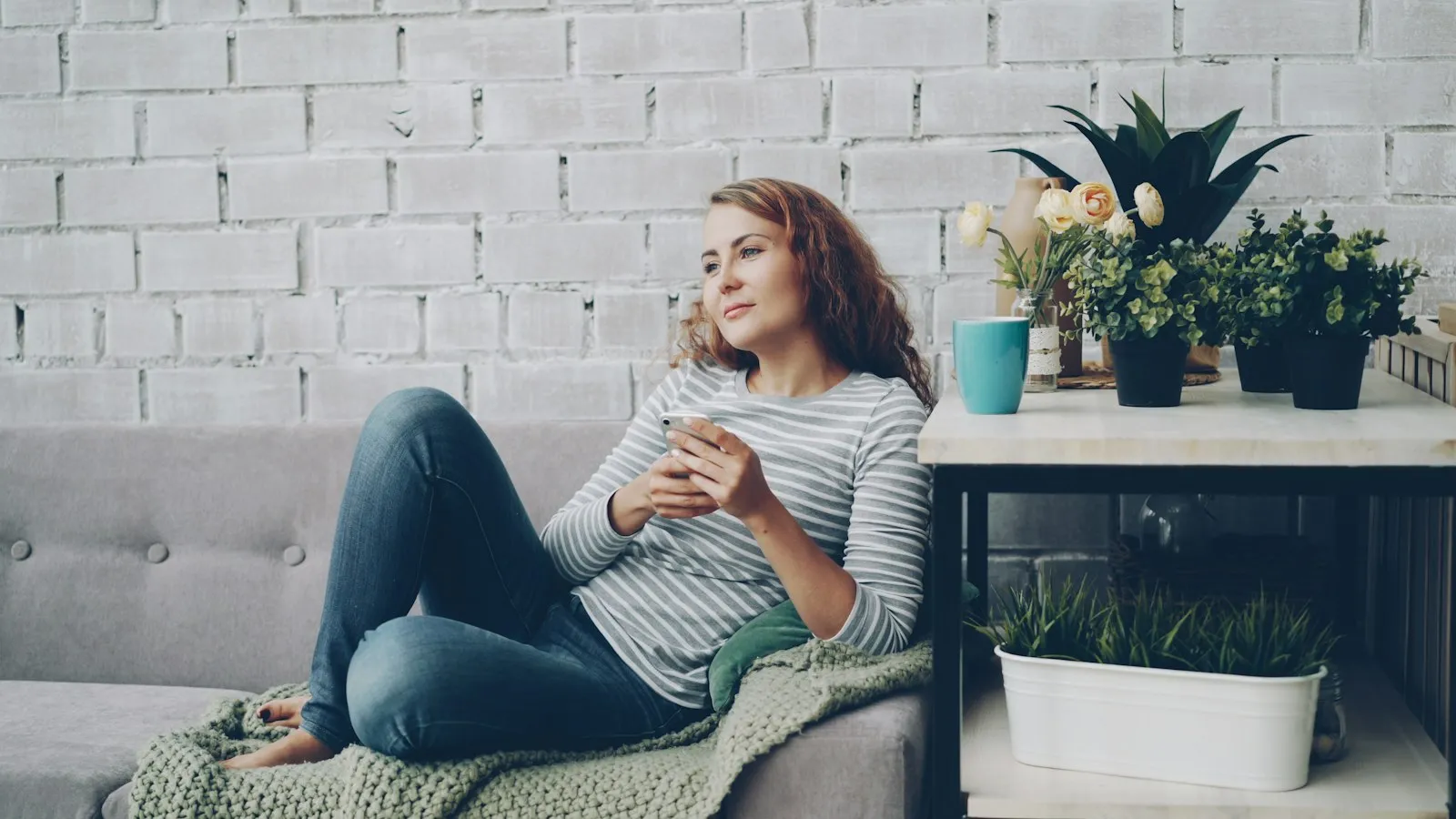A woman relaxing on her sofa playing online bingo on her phone
